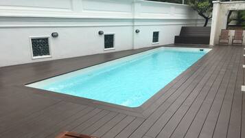 A rectangular swimming pool with a wooden deck surrounding it.
