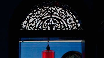 Une entrée agrémentée d’une arche décorative en métal, d’une lanterne rouge, d’une grande plante en pot et d’un tableau encadré au mur.