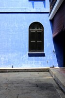 A blue building with a window and a stone-paved area.