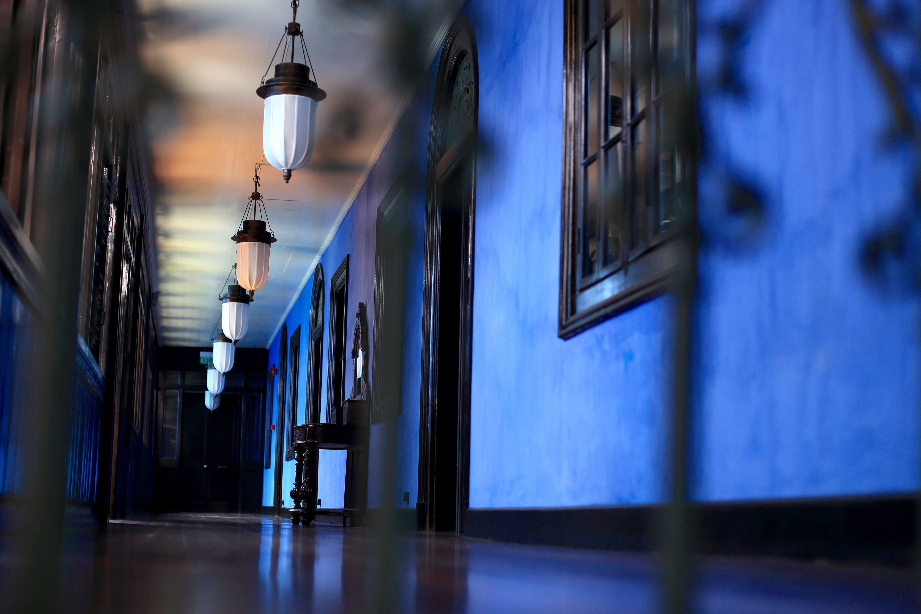 A hallway with hanging lanterns, blue walls, and a wooden floor.
