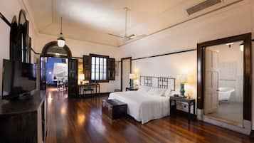 A spacious hotel room with a large bed, a television, a desk, and a bathroom with a bathtub.