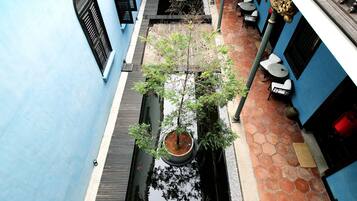 A narrow alley with a tree in a planter, tiled walls, and a small water feature.