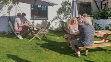 Relax in the serene outdoor patio surrounded by a lush lawn and a charming building.