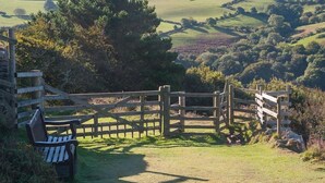A wooden fence with a bench in the foreground and a view of rolling hills in the background. - St Vincent Guest House (Lynton)