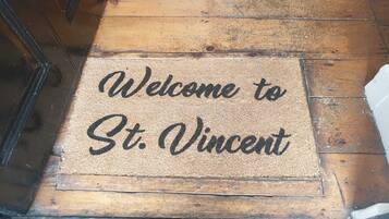 Un felpudo con el texto 'Welcome to St. Vincent' sobre un piso de madera.