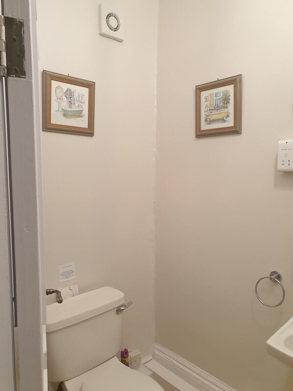 A bathroom with a toilet, a sink, and two framed pictures on the wall. - St Vincent Guest House (Lynton)