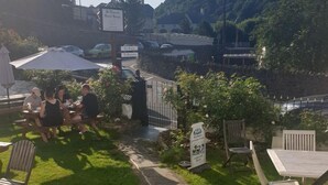 An outdoor seating area with tables and chairs, a stone pathway, and a view of a hill. - St Vincent Guest House (Lynton)