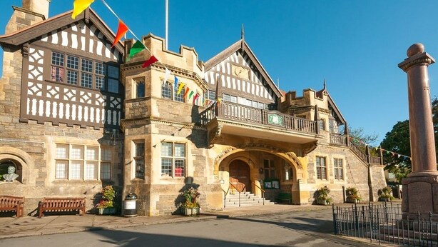 A historic building with a prominent entrance, multiple flags, and a stone facade. - St Vincent Guest House (Lynton)