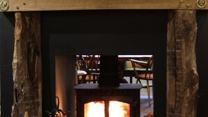 A fireplace with a log fire, framed owl artwork above, and a candle on either side. - The Wheatsheaf Inn (Kendal)