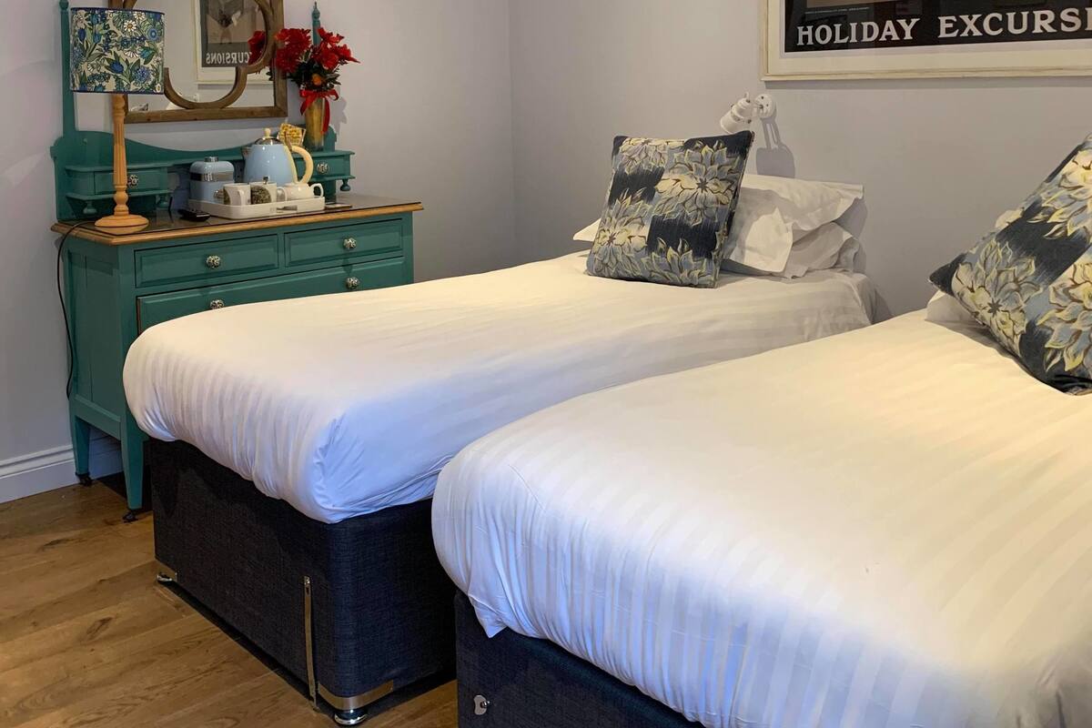 A bedroom with two beds, a dresser, a mirror, and a poster on the wall.