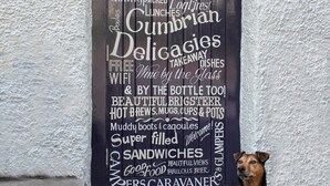 A blackboard with white text advertising a restaurant, including amenities like dogs welcome, open all day, and free wifi. - The Wheatsheaf Inn (Kendal)