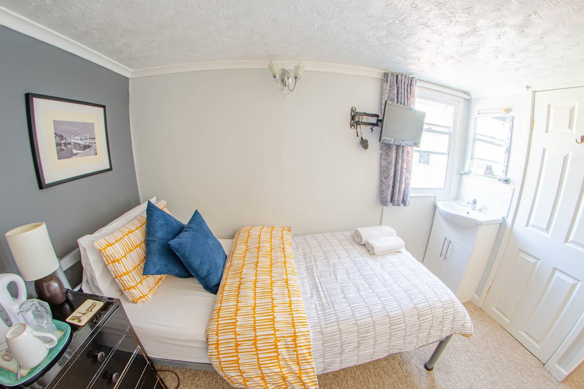 A bedroom with a bed, bedside table, lamp, and a framed picture on the wall.