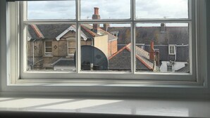 A window with a view of a residential area, including houses and a chimney. - Olivers Guest House (Weymouth)