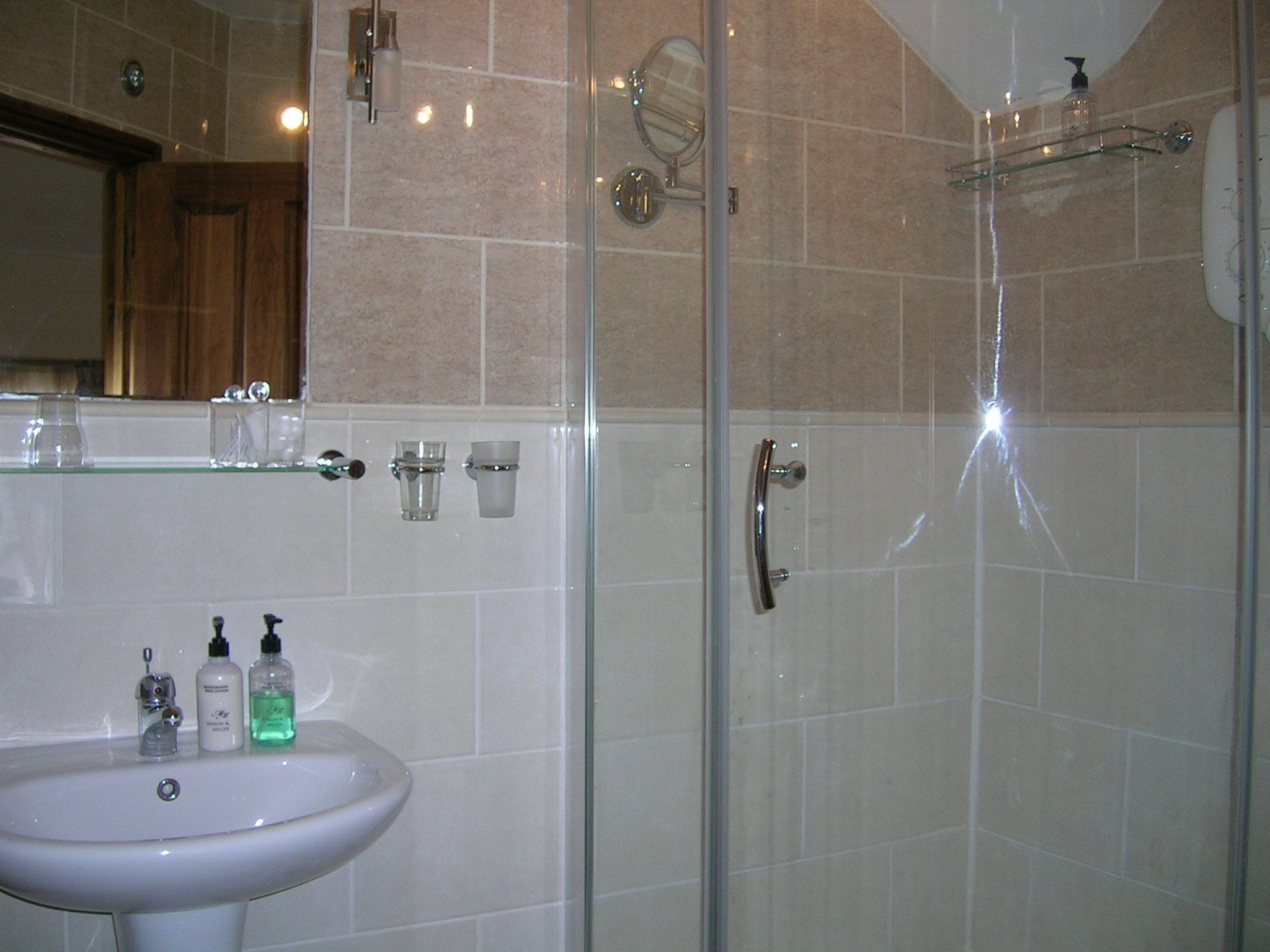 Un baño con lavamanos, espejo y ducha.