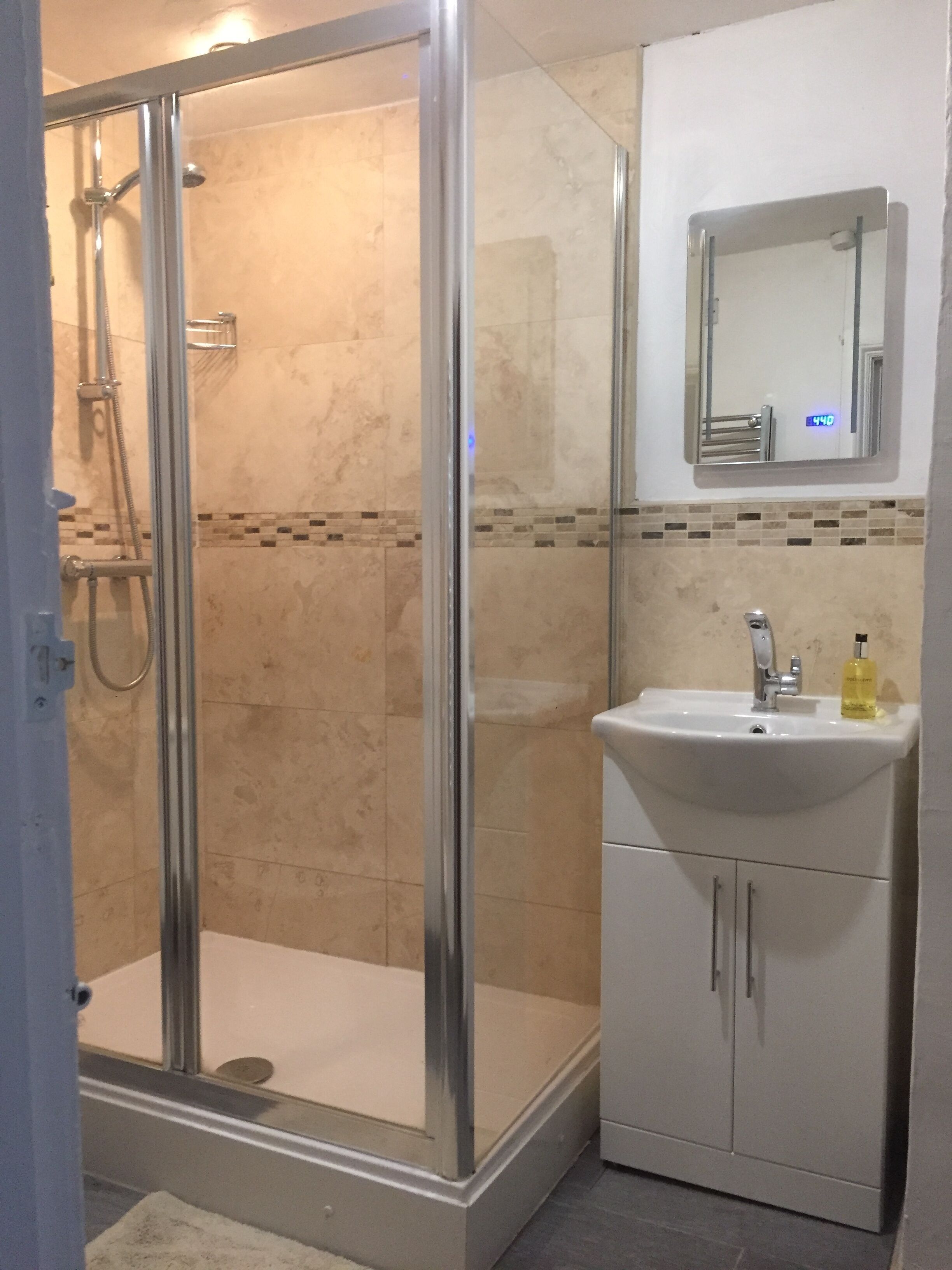 A bathroom with a glass-enclosed shower, a white sink with a mirror above it, and a tiled backsplash.