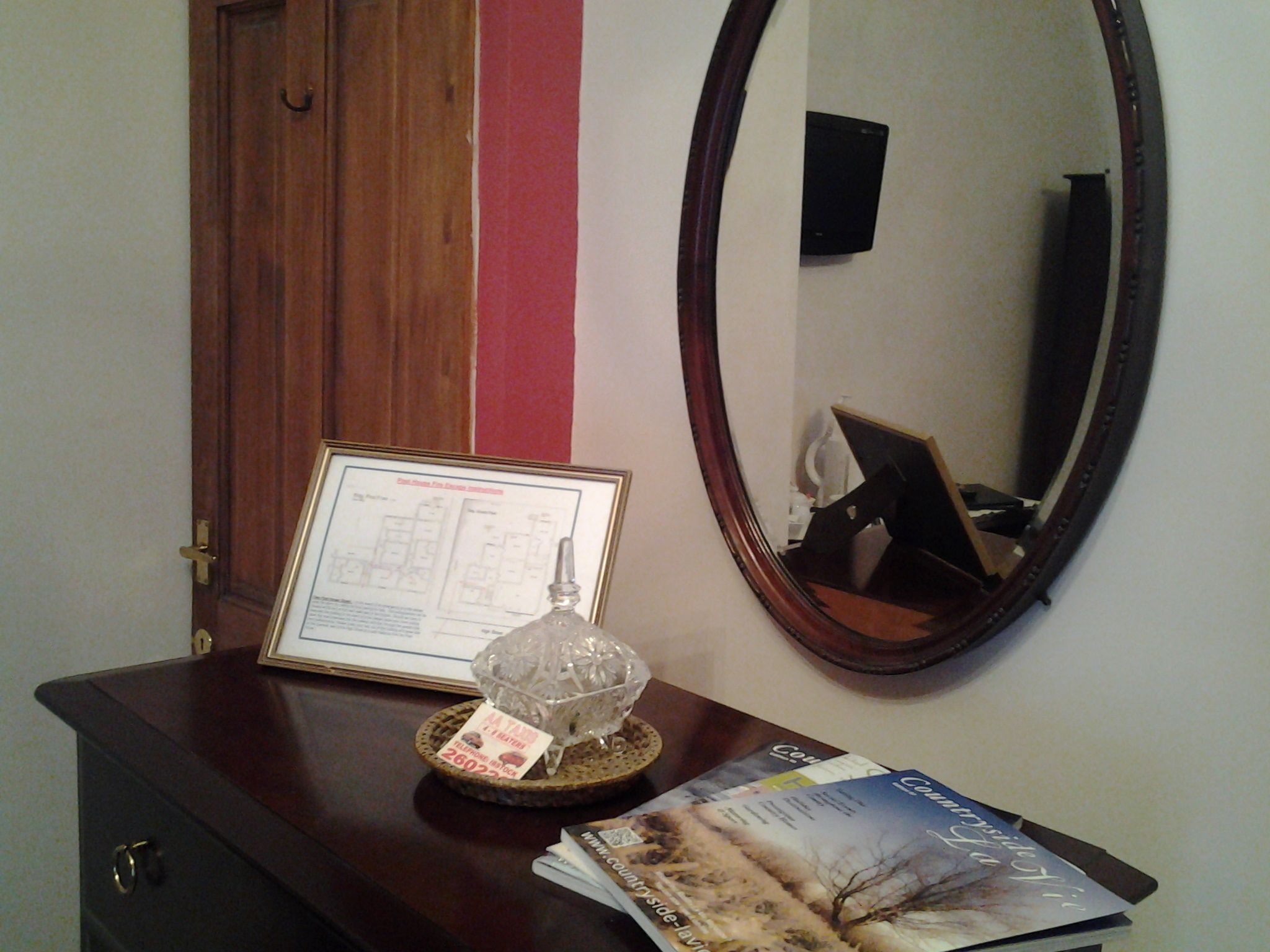 A wooden dresser with a framed certificate, a decorative glass object, and a magazine.
