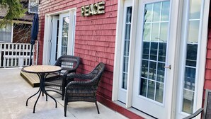 A red building with a 'PEACE' sign, two wicker chairs, and a small table on the porch. - Redwood Bed and Breakfast (Niagara Falls)