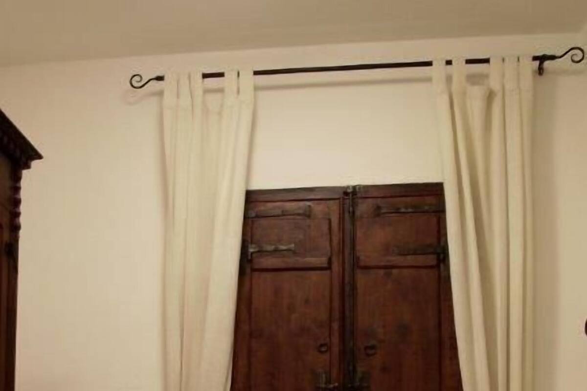 A room with a bed, a window with curtains, and a wooden door.
