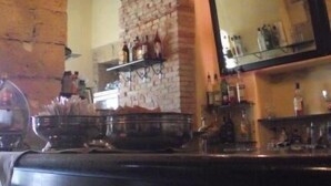 A restaurant interior with a chandelier, stone wall, and bar area. - Cagliari Castello Affittacamere (Cagliari)