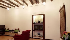 Een woonkamer met zichtbare houten balken, een rode fauteuil, een aquarium en een televisietoestel.