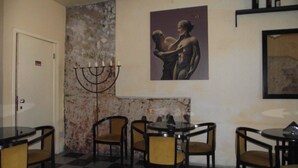 A dining area with round tables and chairs, a menorah, and a painting on the wall. - Cagliari Castello Affittacamere (Cagliari)