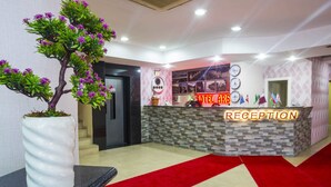 A reception area with a reception desk, a potted plant, and a red carpet. - Arsen Hotel (Arsin)