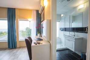 Ett modernt hotellrum med ett skrivbord, en bärbar dator och utsikt över en motorväg.