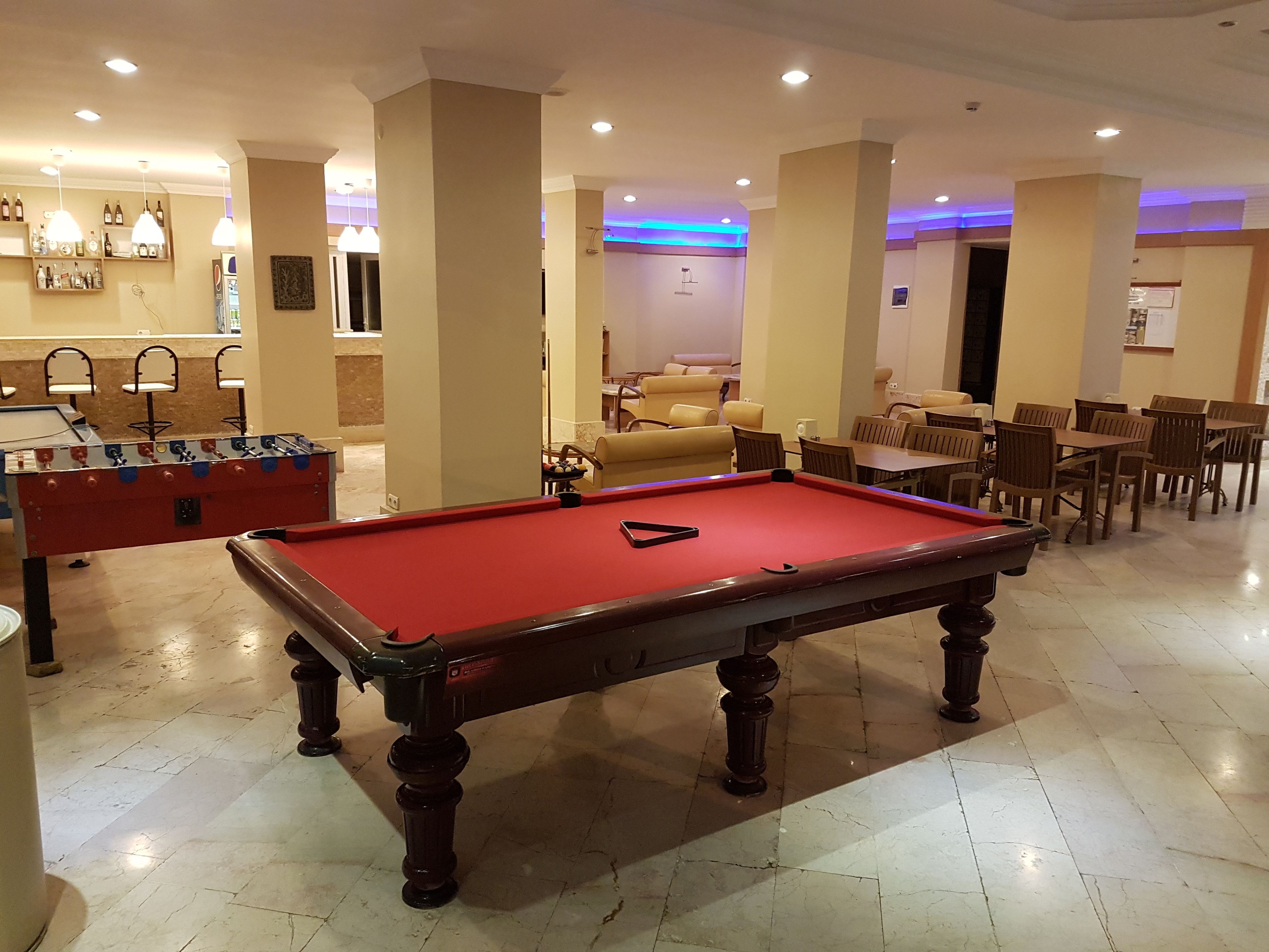 Une table de billard dans une pièce bien éclairée, avec une table de baby-foot et un coin salon.