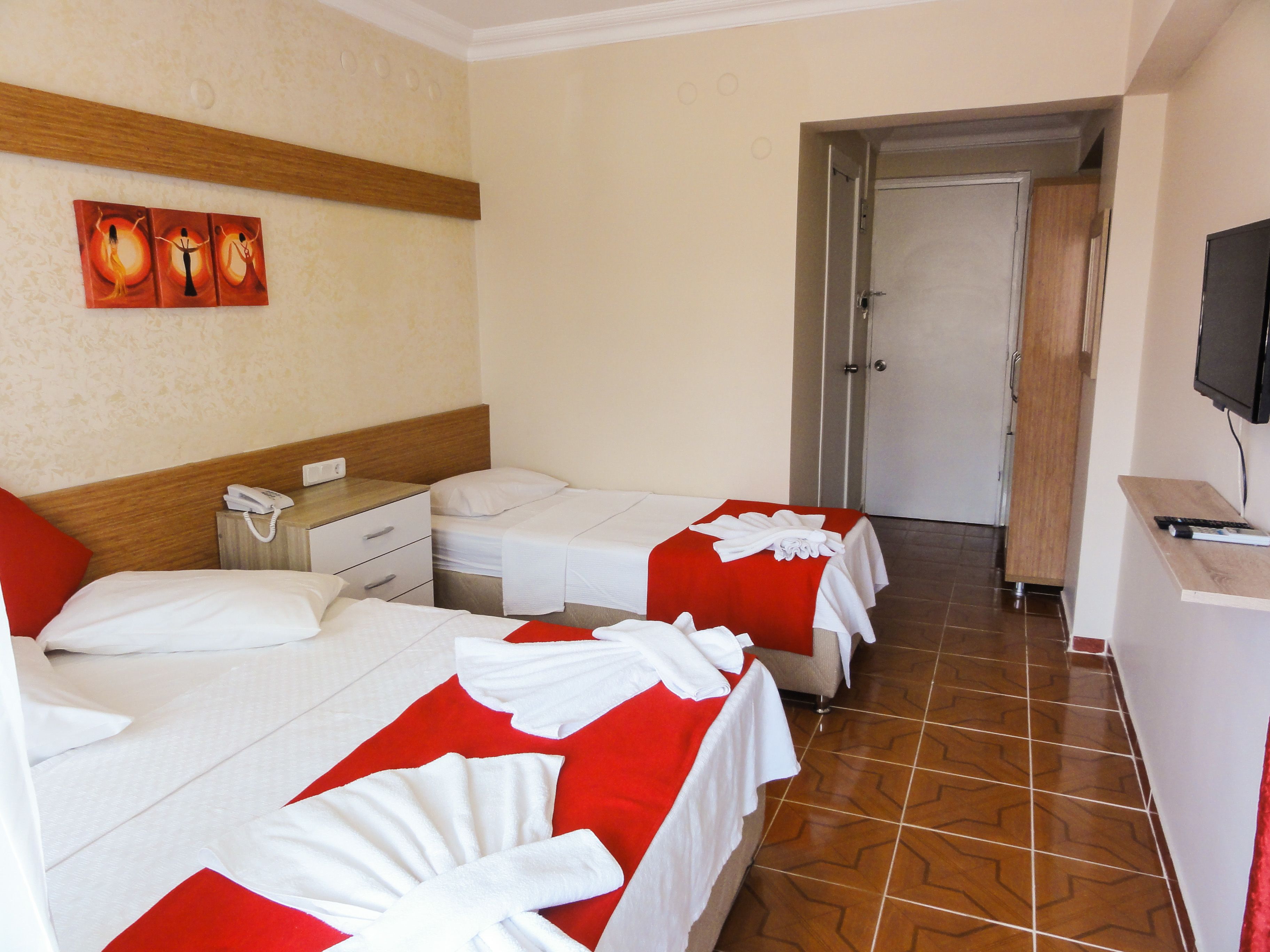 A hotel room with two beds, a wooden headboard, a telephone, a TV, and a painting on the wall.