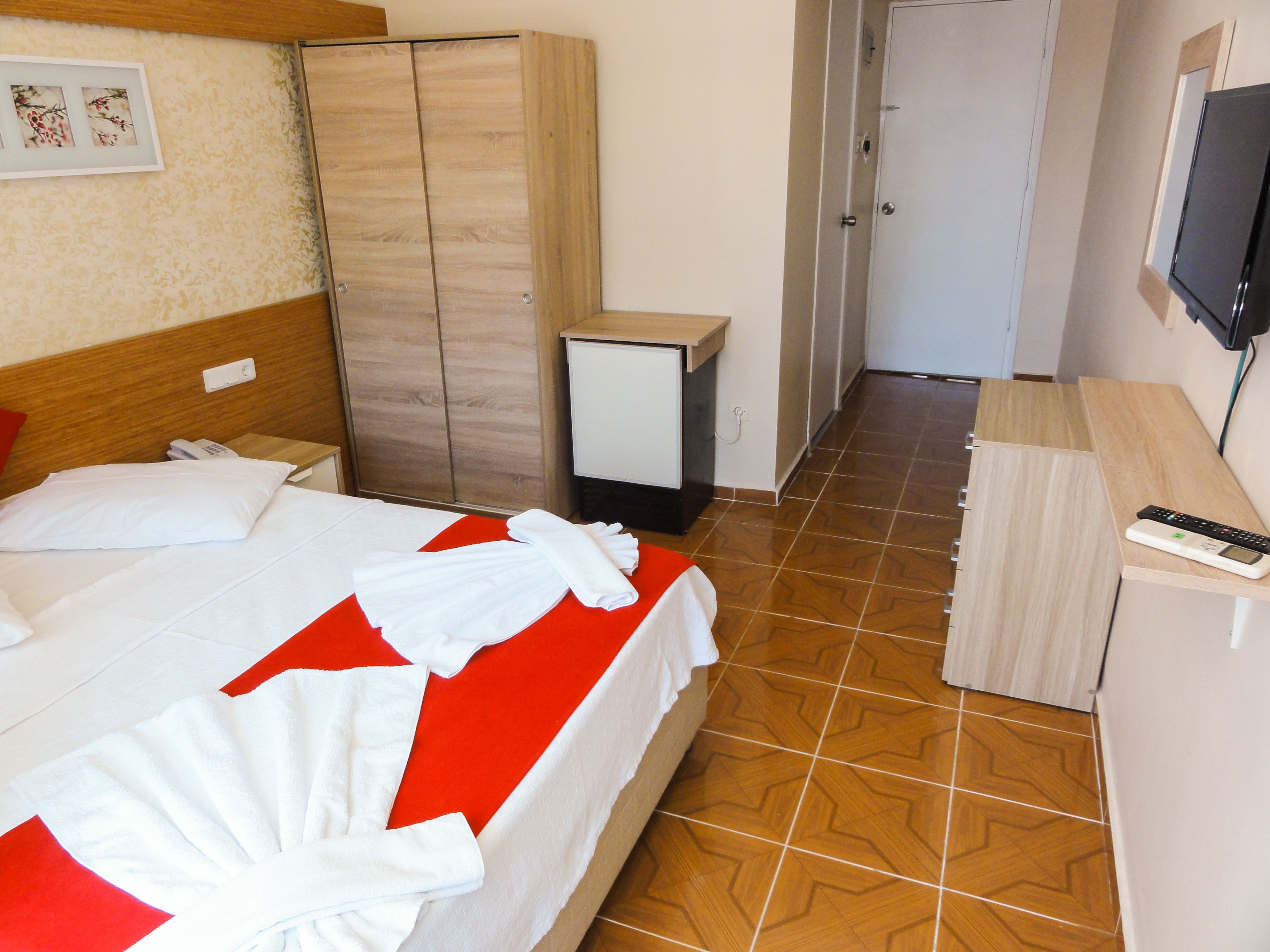 Ein Hotelzimmer mit Bett, Schrank, Schreibtisch und Fernseher.
