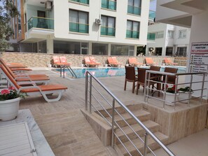 A poolside area with lounge chairs and a pool.
