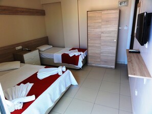 Quarto de hotel com duas camas, cabeceira de madeira, televisão e porta deslizante.