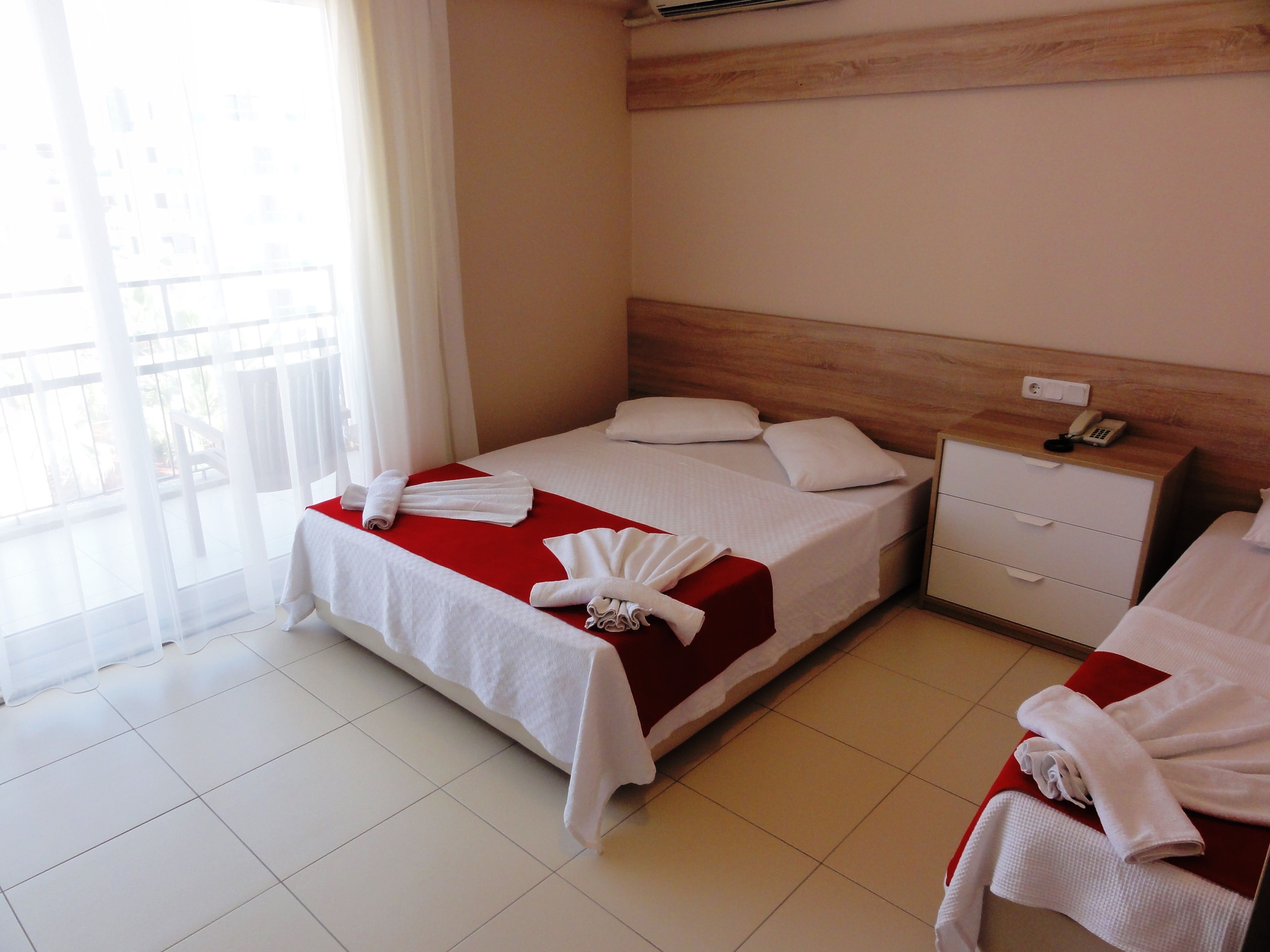 A hotel room with a bed, a nightstand, and a red accent wall.