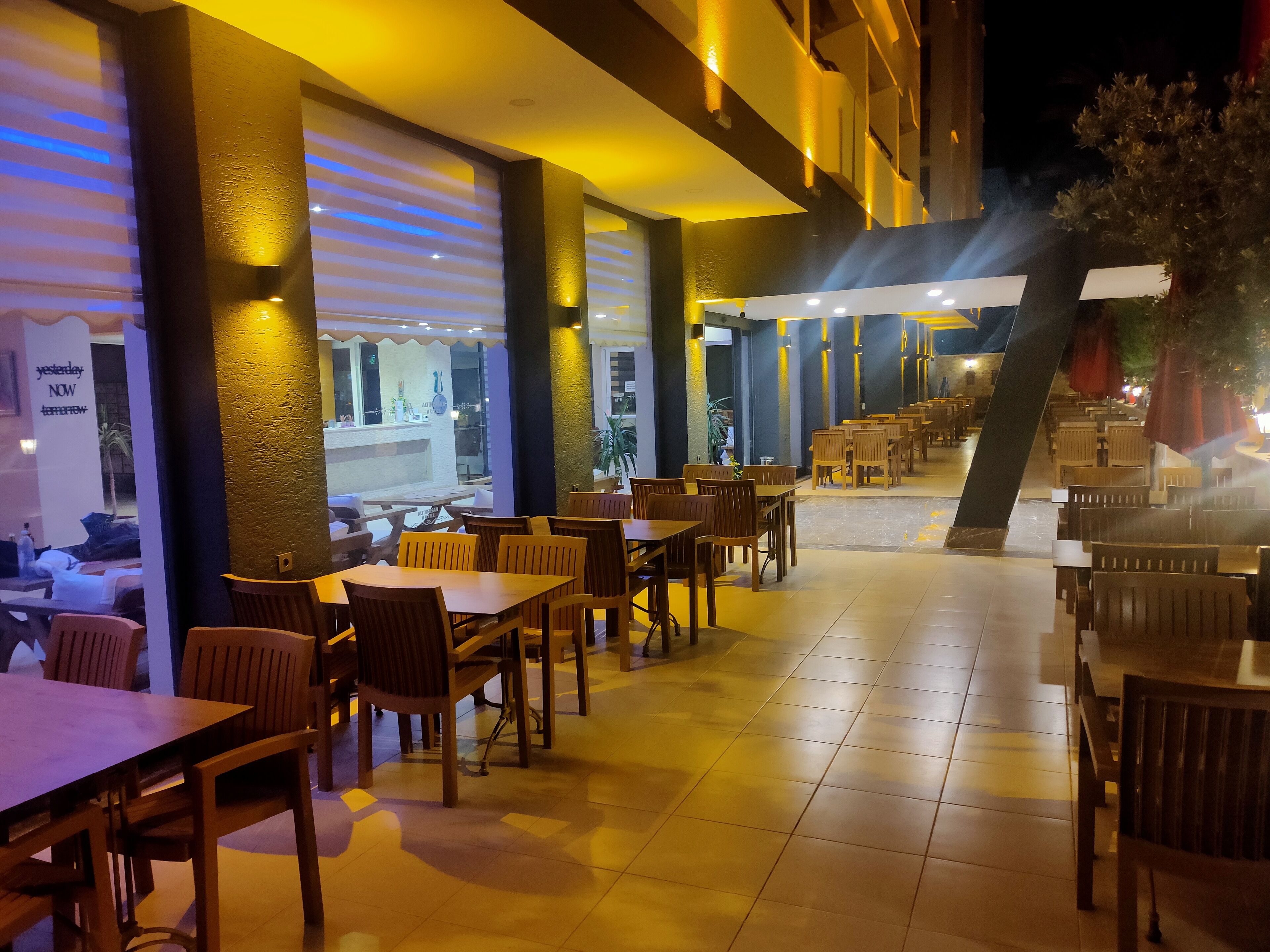 Ein Restaurant mit Holztischen und -stühlen, einem Fliesenboden und Blick auf die Straße.