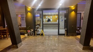 Eine Hotelhalle mit einer Rezeption, einem Fahrrad und einem gelben Warnschild.