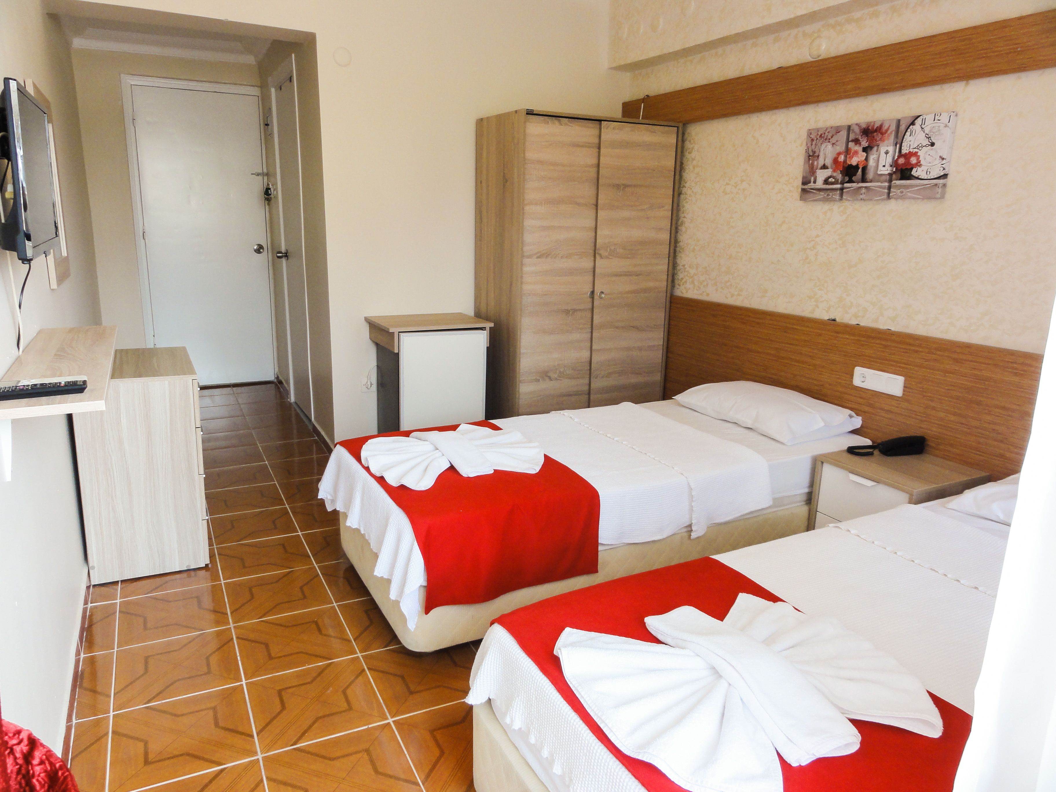 Une chambre d’hôtel avec deux lits, un petit bureau, une armoire et un téléviseur.