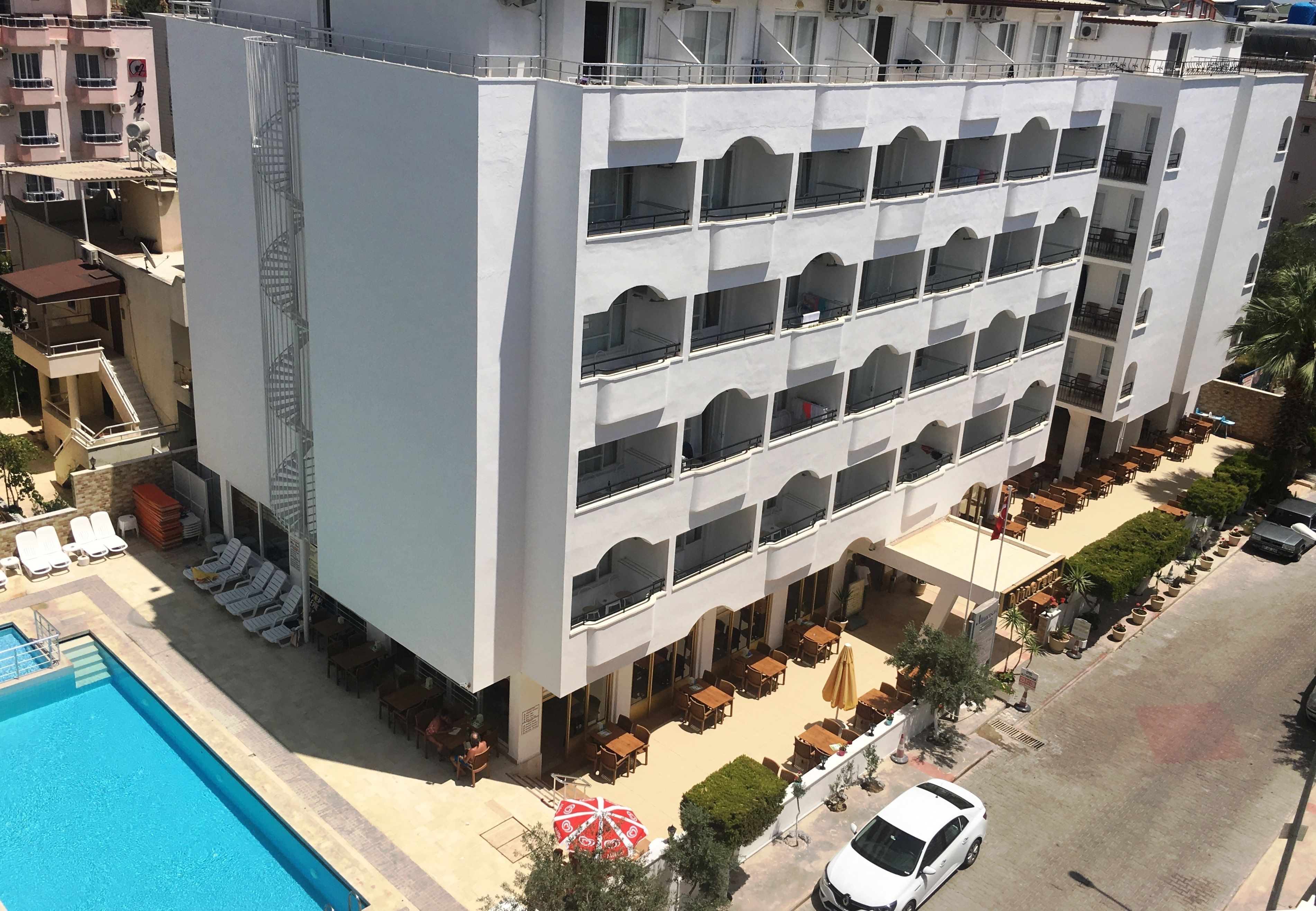 A multi-story hotel with balconies, a pool, and outdoor seating areas.