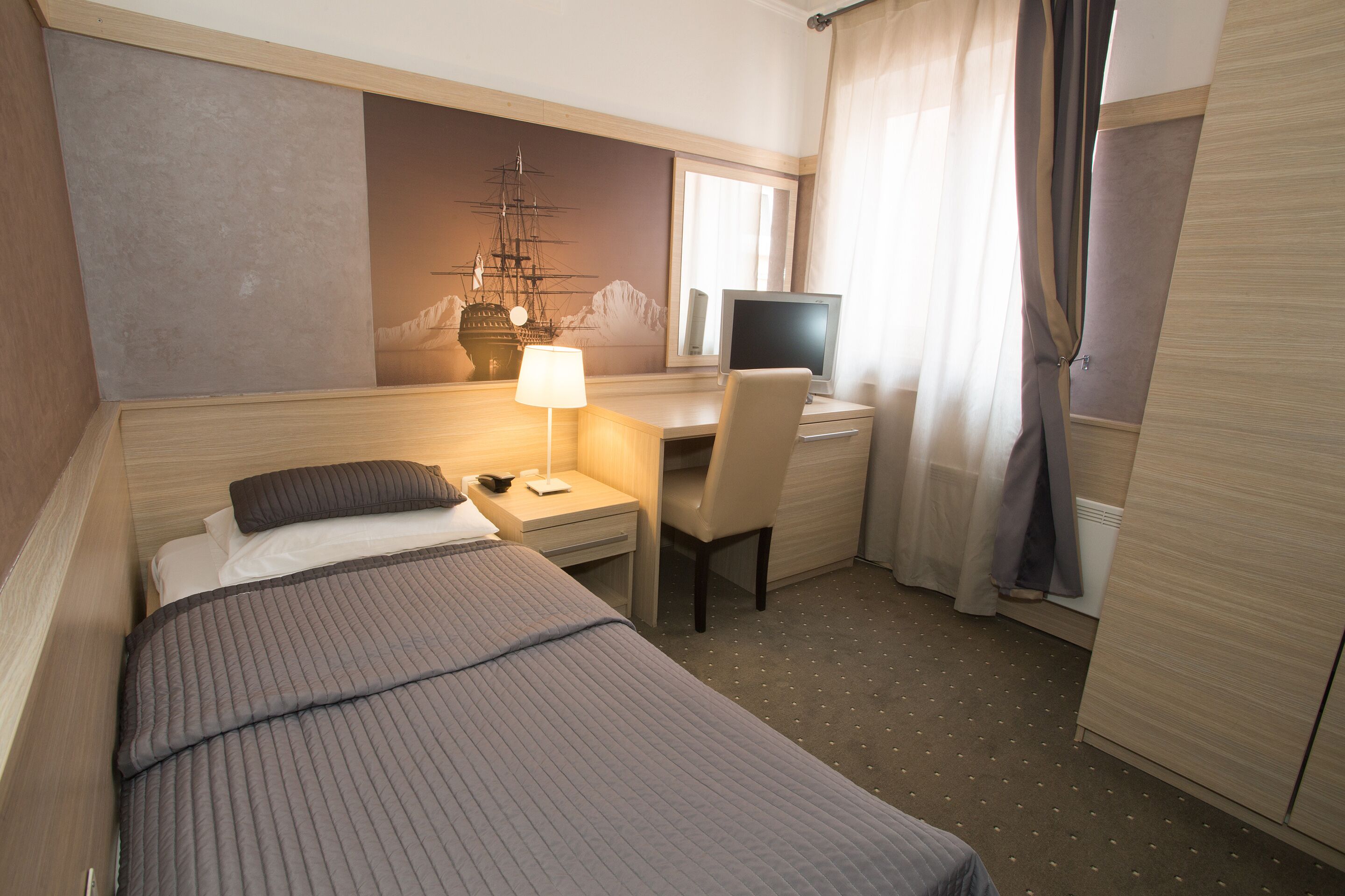 Una habitación de hotel con cama, escritorio con ordenador, silla y decoración marina en la pared.