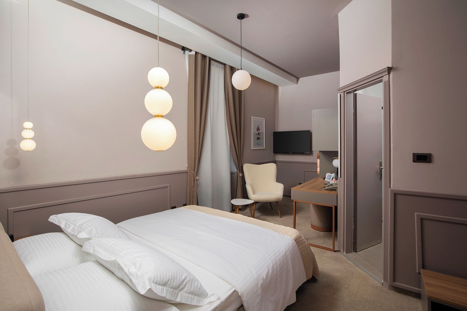 Une chambre d’hôtel avec un lit, une chaise, un bureau, une télévision et une porte.
