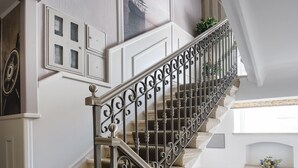 Un escalier orné de rampes en métal décoratif et recouvert d’une moquette à motifs.