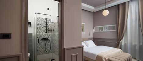 A bedroom with a bed, a bedside table, a mirror, and a shower area with a glass door.