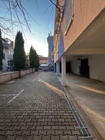 A paved courtyard with a brick pattern, surrounded by buildings and trees.