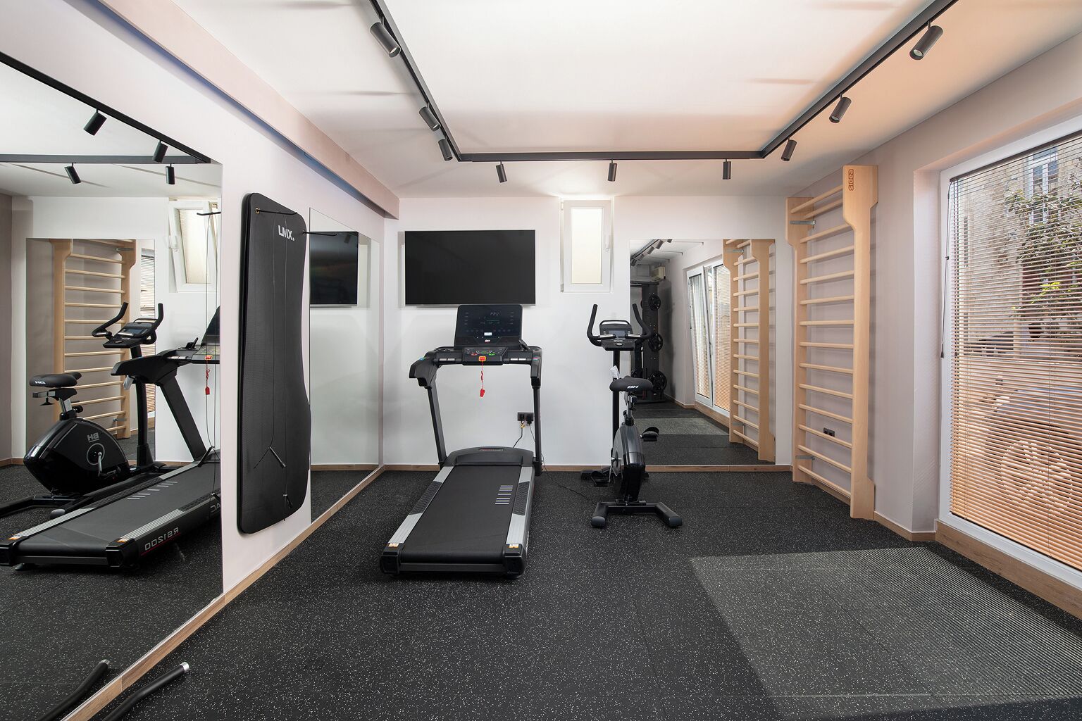Un gimnasio con cintas de correr, bicicletas estáticas y un espejo grande.