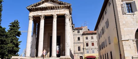 A classical building with columns, a central entrance, and a red awning.