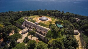 Vue aérienne d’un site historique comprenant des ruines antiques, une vaste structure circulaire et un bâtiment doté d’un toit végétalisé.
