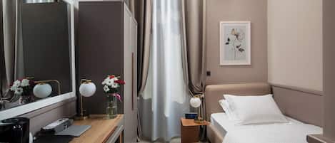 Camera d'albergo con un letto, comodino, lampada, specchio e condizionatore d'aria a parete.