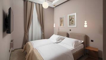A modern bedroom with a bed, curtains, artwork, and a television.