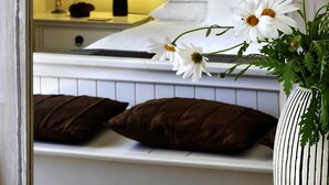 A bedroom with a bed, pillows, a nightstand with a lamp, and a vase with flowers. - Alba House Bed & Breakfast (Paarl)