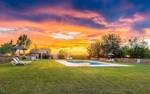 Una piscina al aire libre, sombrillas, sillones reclinables de piscina