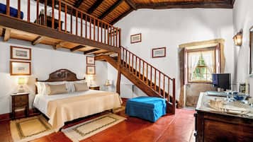 Une chambre avec un escalier en bois, un lit recouvert d’une courtepointe, une table de chevet, une table ornée d’objets décoratifs et une fenêtre avec des rideaux.